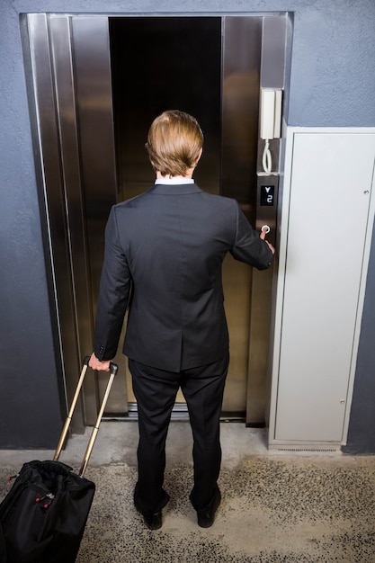 Businessman pressing elevator button in office