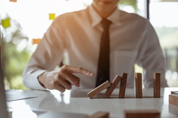 Businessman pulling or placing long wooden blocks in a modern office Indicates the impact