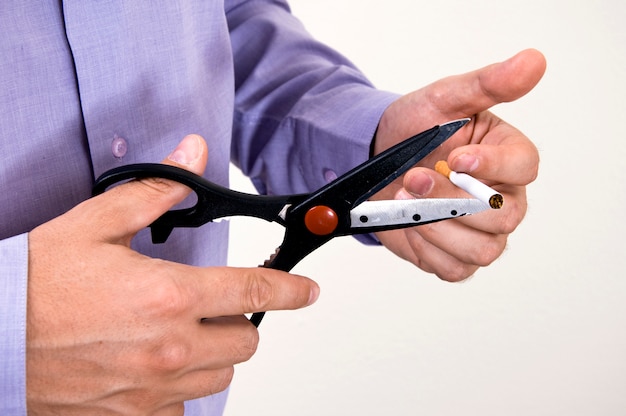 Businessman in purple shirt is cutting a cigarette with scissors