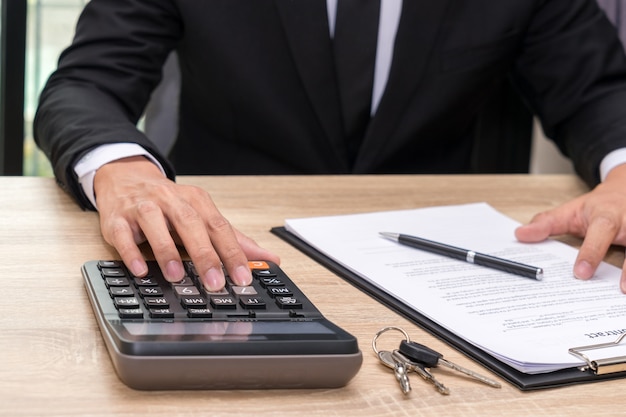 Photo businessman pushing calculator on wooden desk - buy home concept.