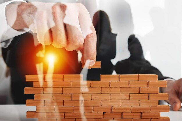 ビジネスマンは、新しいビジネス パートナーシップの統合とスタートアップの壁の概念を構築するためにレンガを置きます