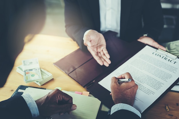 Businessman puts signature on contract at business meeting and passing money after negotiations