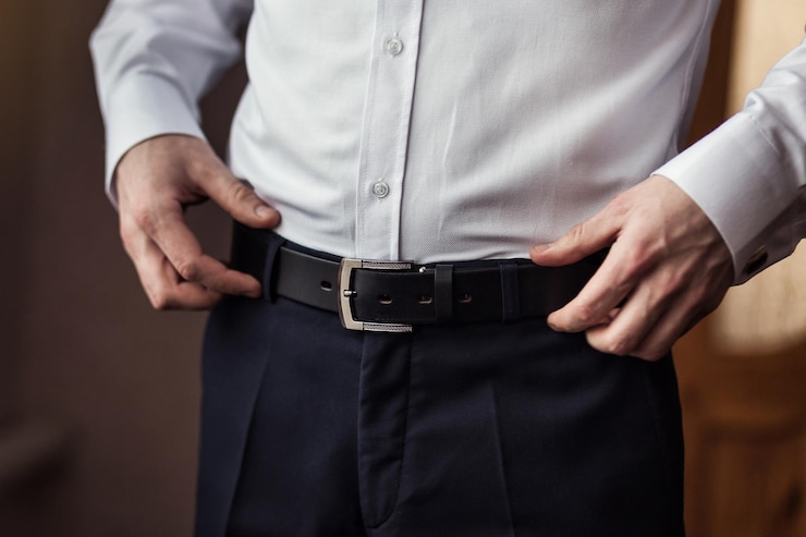 Photo businessman putting on a belt fashion and clothing conceptgroom getting ready in the morning before ceremony