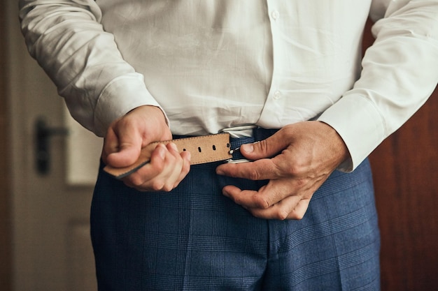 Foto uomo d'affari che indossa una cintura di moda e abbigliamento conceptgroom si prepara al mattino prima della cerimonia