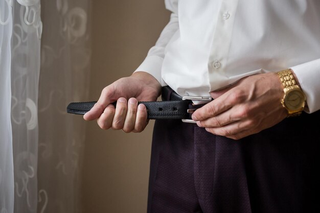 Businessman putting on a belt fashion and clothing conceptgroom getting ready in the morning before ceremony