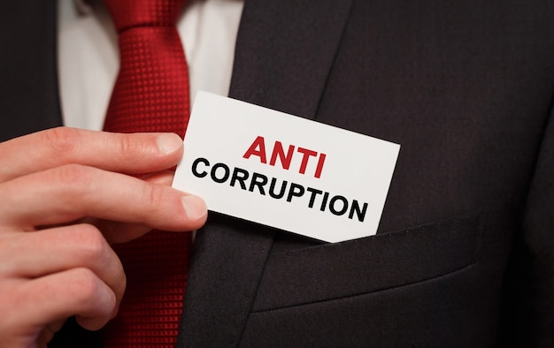 Businessman putting a card with text anti corruption in the pocket