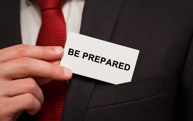 Businessman putting a card with text Be Prepared in the pocket