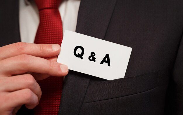 Businessman putting a card with text Q and A in the pocket