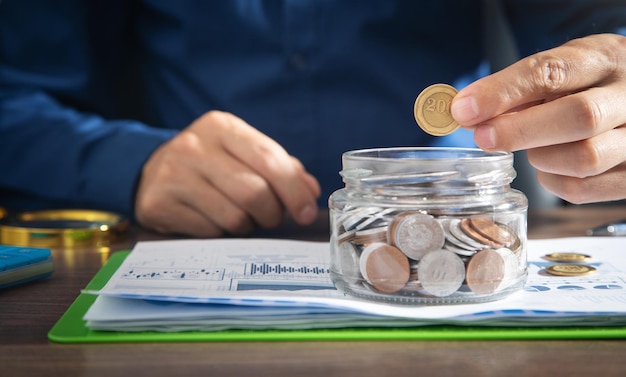 Businessman putting coin in glass bank Saving money