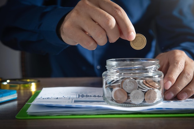 Businessman putting coin in glass bank Saving money