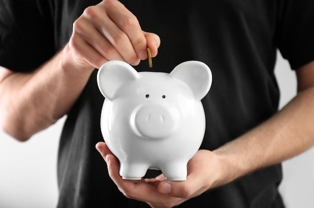 Businessman putting coin into the piggy bank