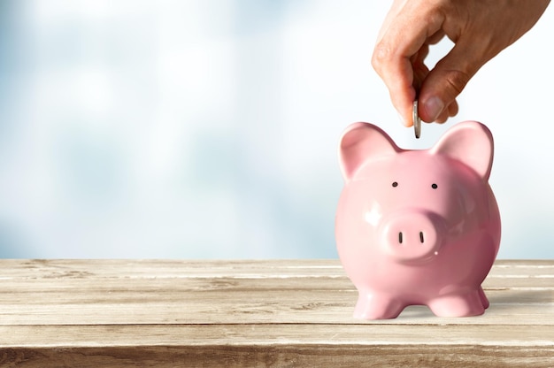 Businessman putting coin into the piggy bank