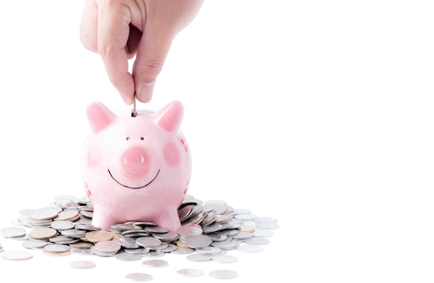 Businessman putting coin into pink piggy bank 