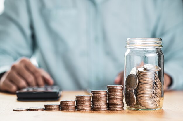 Businessman putting coins to savings jar