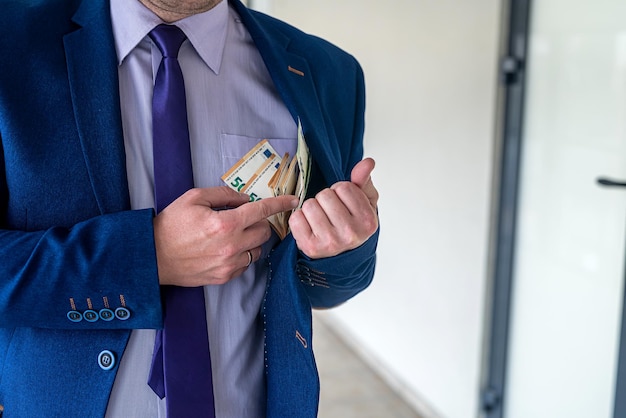 Businessman putting euro bills into pocket hit jacket. bribe  corruption concept