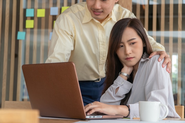 Businessman putting hand on the shoulder of female employee in office at work.