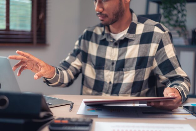 Бизнесмен читает деловой документ, проверяет финансовый и бухгалтерский отчет на ноутбуке в офисе