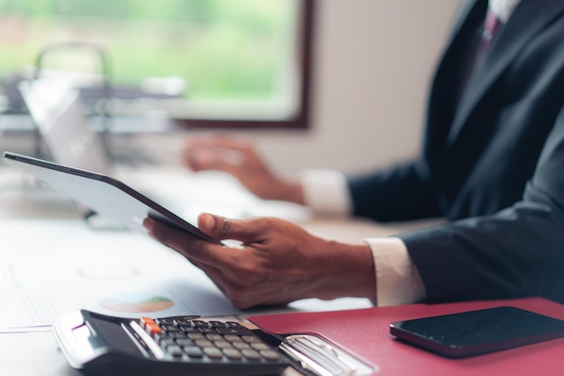 Businessman read data on tablet to checking financial and accounting report of business on laptop