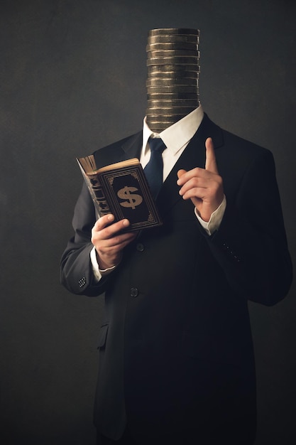 businessman reading book with stacked coins head against black background