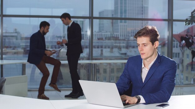 Businessman reading news on laptop computer at coworking space.