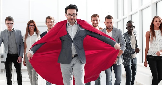 赤いマントを着たビジネスマンがビジネスチームを率いる