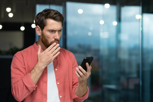 赤いシャツを着たビジネスマンは、電話で悪いニュース メッセージのオンライン メッセージを受け取りました。