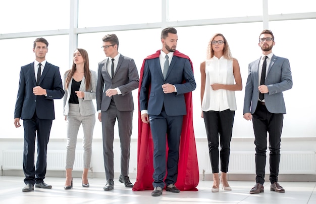 Businessman in a red superhero cloak and his business teamphoto with copy space