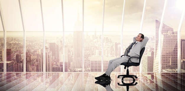 Businessman relaxing in swivel chair against room with large window looking on city