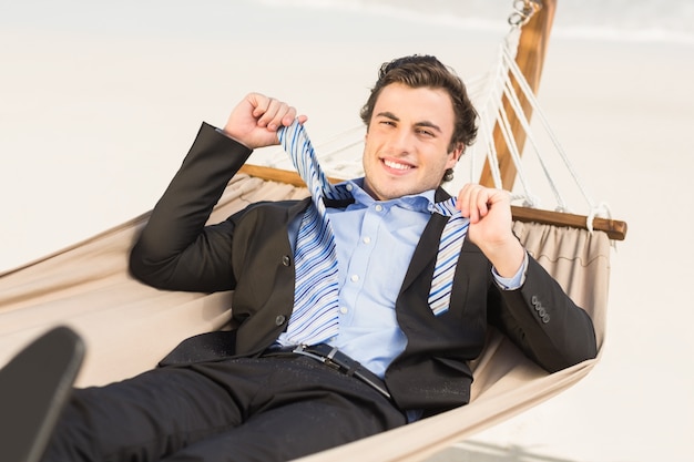 Businessman removing his tie on the hammock