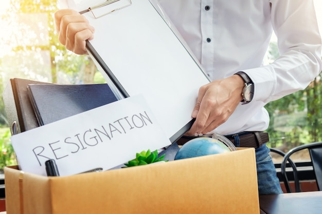 Businessman resignation packing up all his personal belongings and files into a brown cardboard box