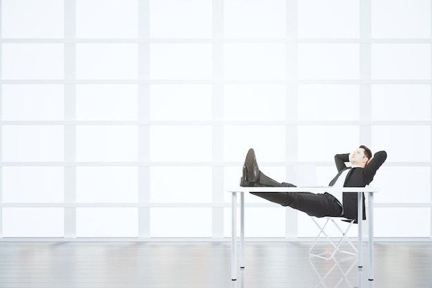 Businessman resting on a chair in light empty loft office