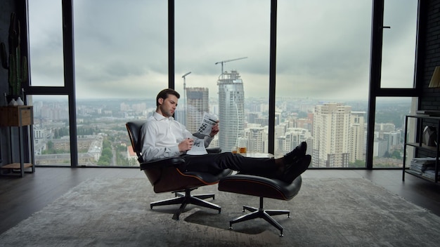 Businessman resting in chair with newspaper manager reading\
newspaper in office