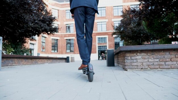 Businessman riding on electric scooter going to business meeting working in startup company office. entrepreneur in suit going at home after working day. Concept of eco-friendly transportation