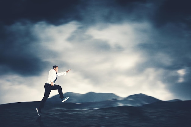 Businessman run fast on mountain with cloudy sky