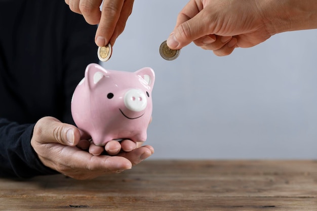 The businessman's hand holds the money in the piggy bank for saving money for future use saving money