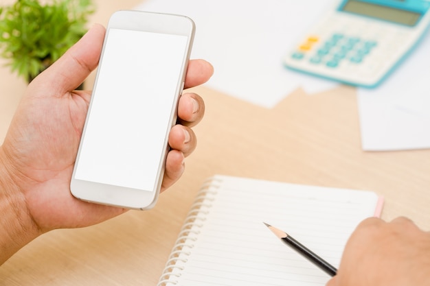 Businessman's hands holding and use mobile phone on on office table