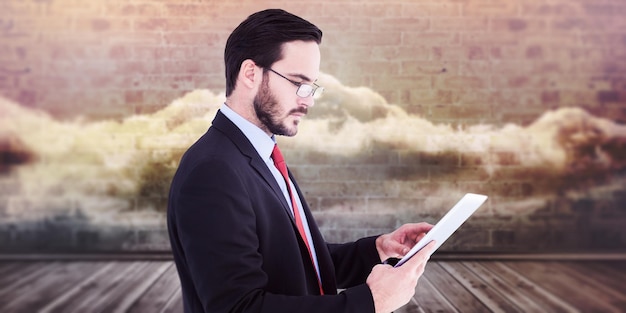 Businessman scrolling on his digital tablet against clouds in a room