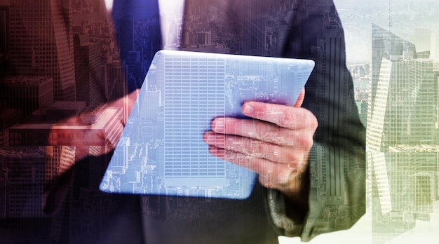 Businessman scrolling on his digital tablet against room with large window looking on city