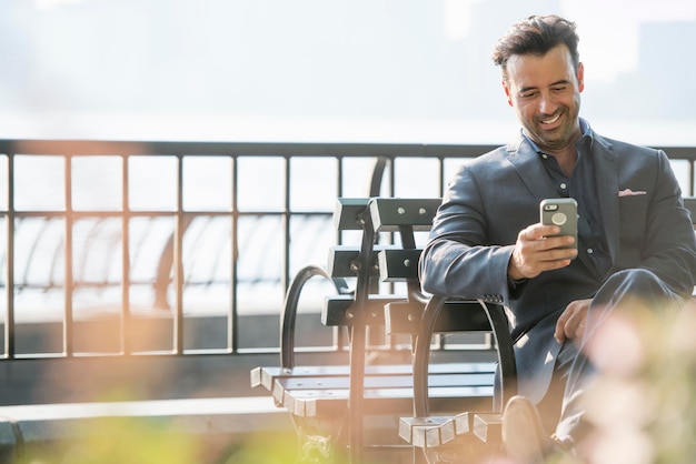 Photo a businessman seated checking his phone laughing