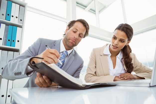 Businessman and secretary looking at diary in office