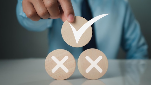 Photo businessman selects correct check mark symbol on wooden circle plank for business proposal