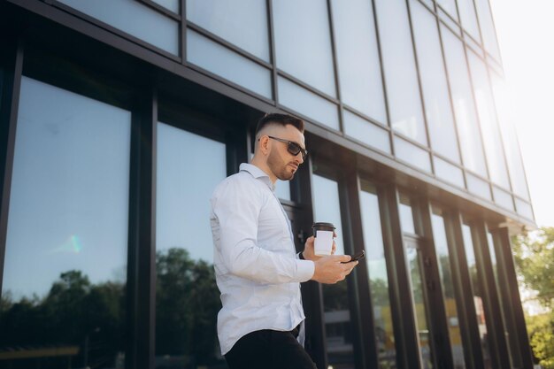 businessman sends a message on the phone on the street on the background of the office