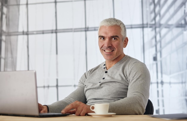 Businessman senior gray hair working laptop interior modern white office