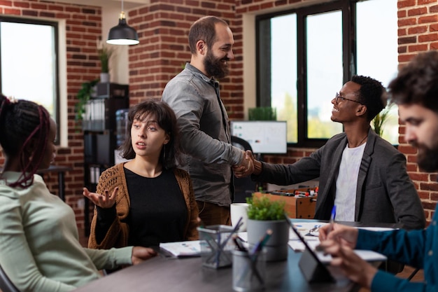 Photo businessman shaking hand with manager during business meeting in startup office. multi-ethnic businesspeople discussing company turnover working at marketing strategy brainstorming ideas