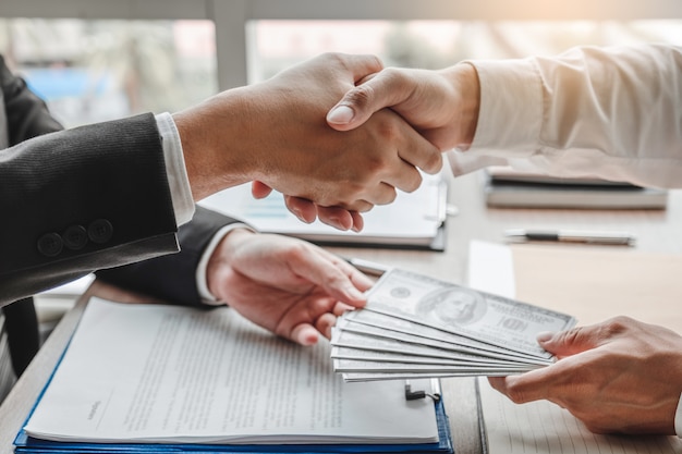 Businessman shaking hands giving dollar bills corruption bribery to business manager to deal contract