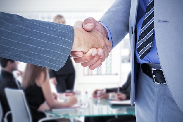 Foto uomo d'affari che stringe la mano a un collaboratore contro la donna d'affari che riferisce alle vendite in un seminario