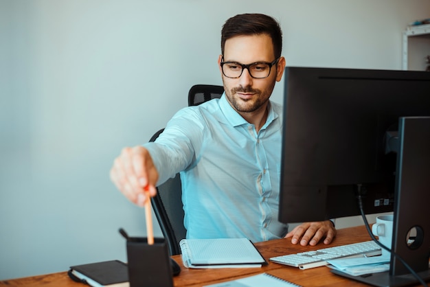 Businessman sharpening pencil in his office.