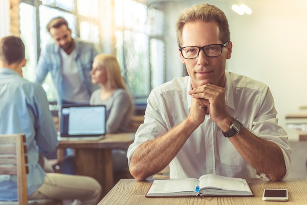 Businessman in shirt and eyeglasses is looking at camera