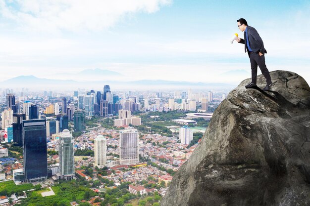 Businessman shout through a megaphone on cliff