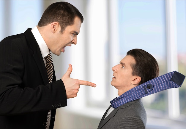 Businessman shouting orders at a worker on background